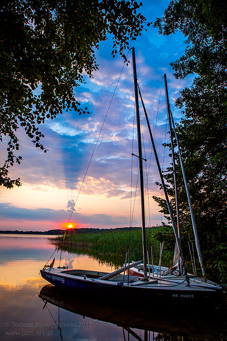 Zachód słońca nad jeziorem na Mazurach z żaglówkami